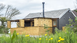 A wooden cabin with a chimney, a window, and a door.