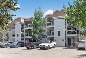 A multi-story residential building with a parking lot in front.