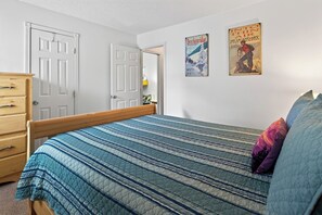 A bedroom with a bed, a dresser, and two posters on the wall.