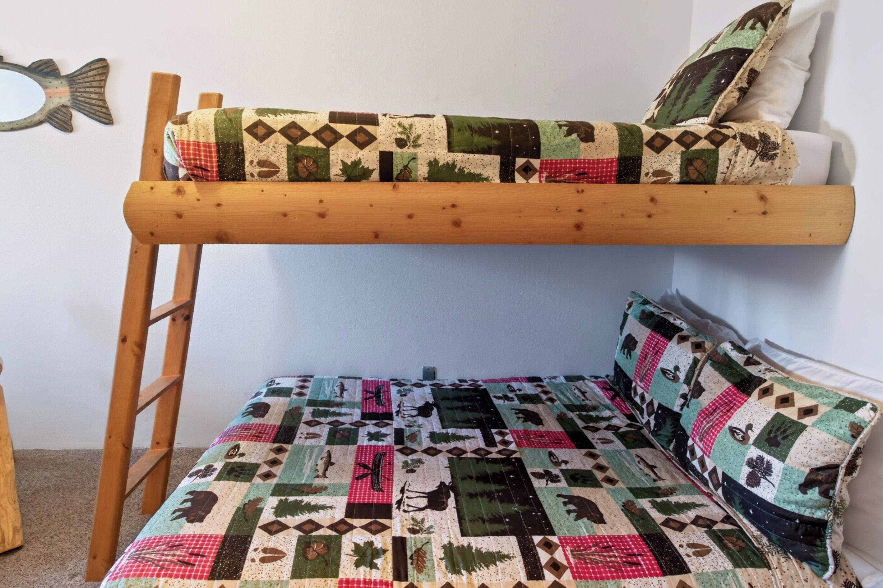 Un lit superposé avec une courtepointe matelassée et une échelle.
