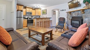 Ein Wohnzimmer mit einem braunen Ledersofa, einem Holztisch und einem Kamin aus Stein.