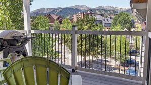 Ein Balkon mit Blick auf ein Gebirge, einem Grill und einem grünen Stuhl.