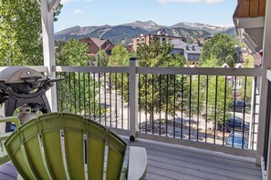 A balcony with a view of a mountain range, a grill, and a green chair. - Right on Main Street Amazing Views of the Ski Area (Breckenridge)