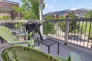A balcony with a grill, chairs, and a view of a mountain landscape. - Right on Main Street Amazing Views of the Ski Area (Breckenridge)
