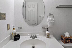 A bathroom with a white sink, a mirror, a towel rack, and toiletries.