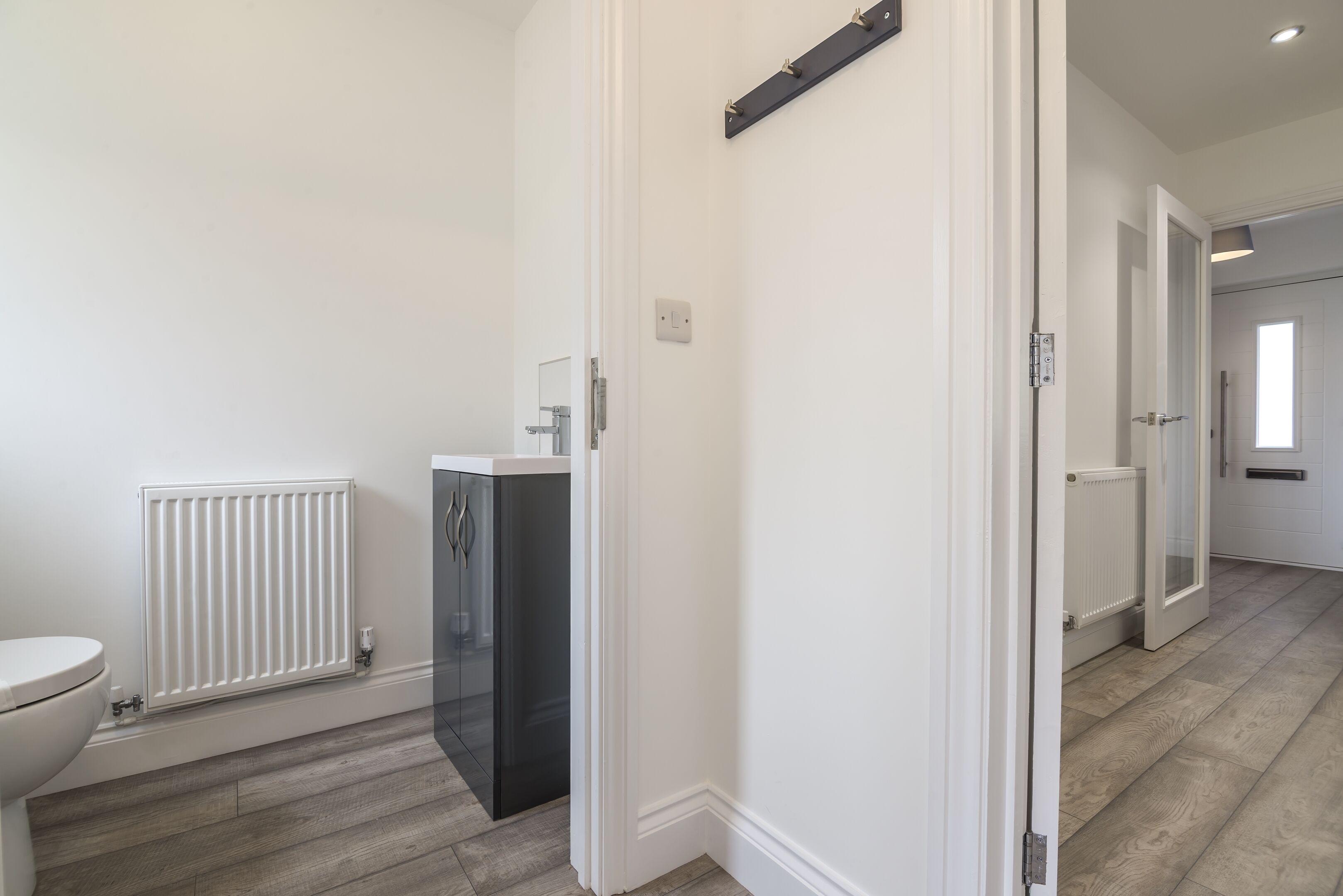Un baño moderno con inodoro, radiador blanco y mueble negro.