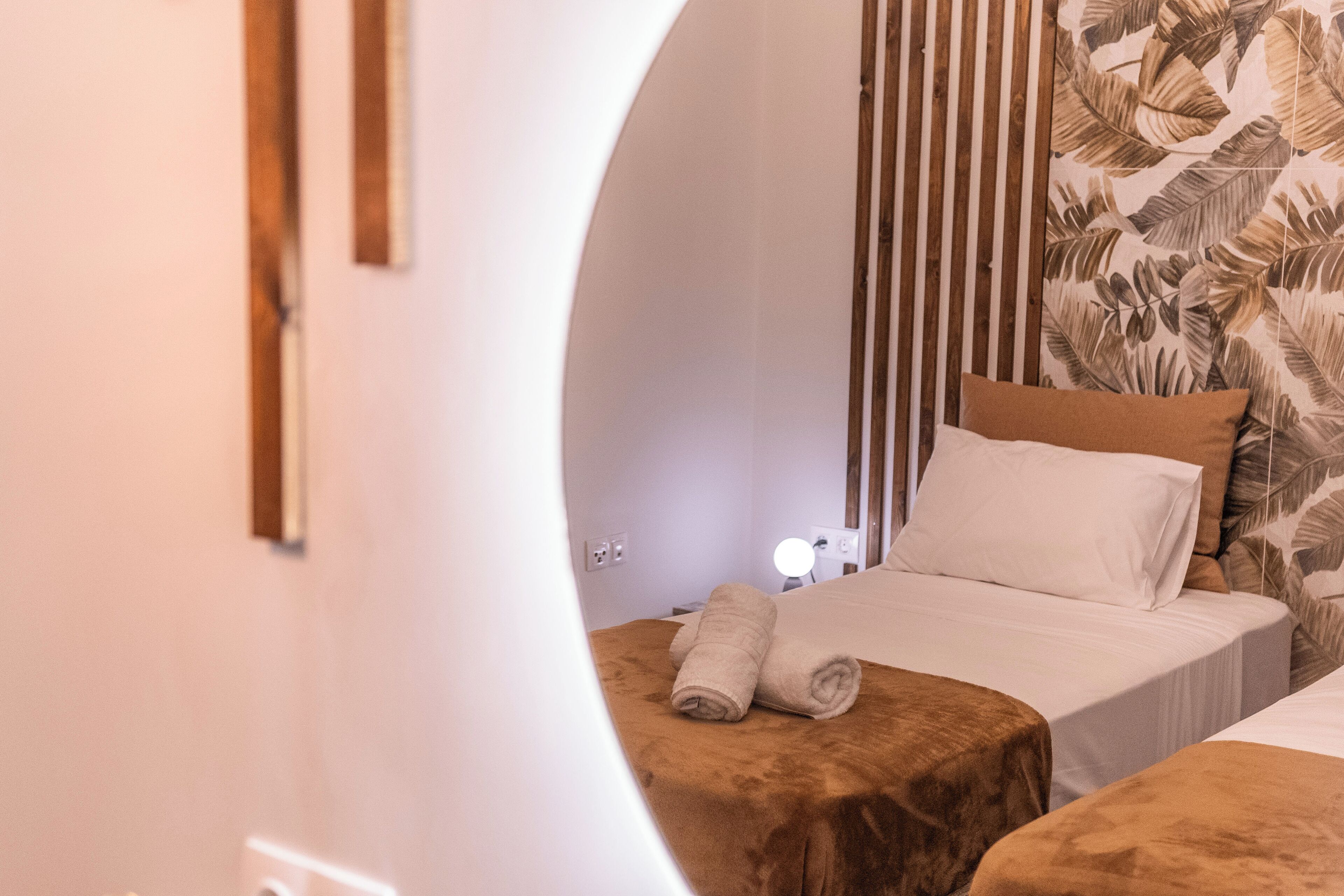 A bedroom with two beds, a wooden headboard, and a wall with a leaf pattern.