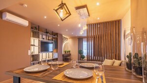 Un comedor moderno con una mesa de madera dispuesta para cuatro personas, rodeada de estanterías y un rincón de estar acogedor.