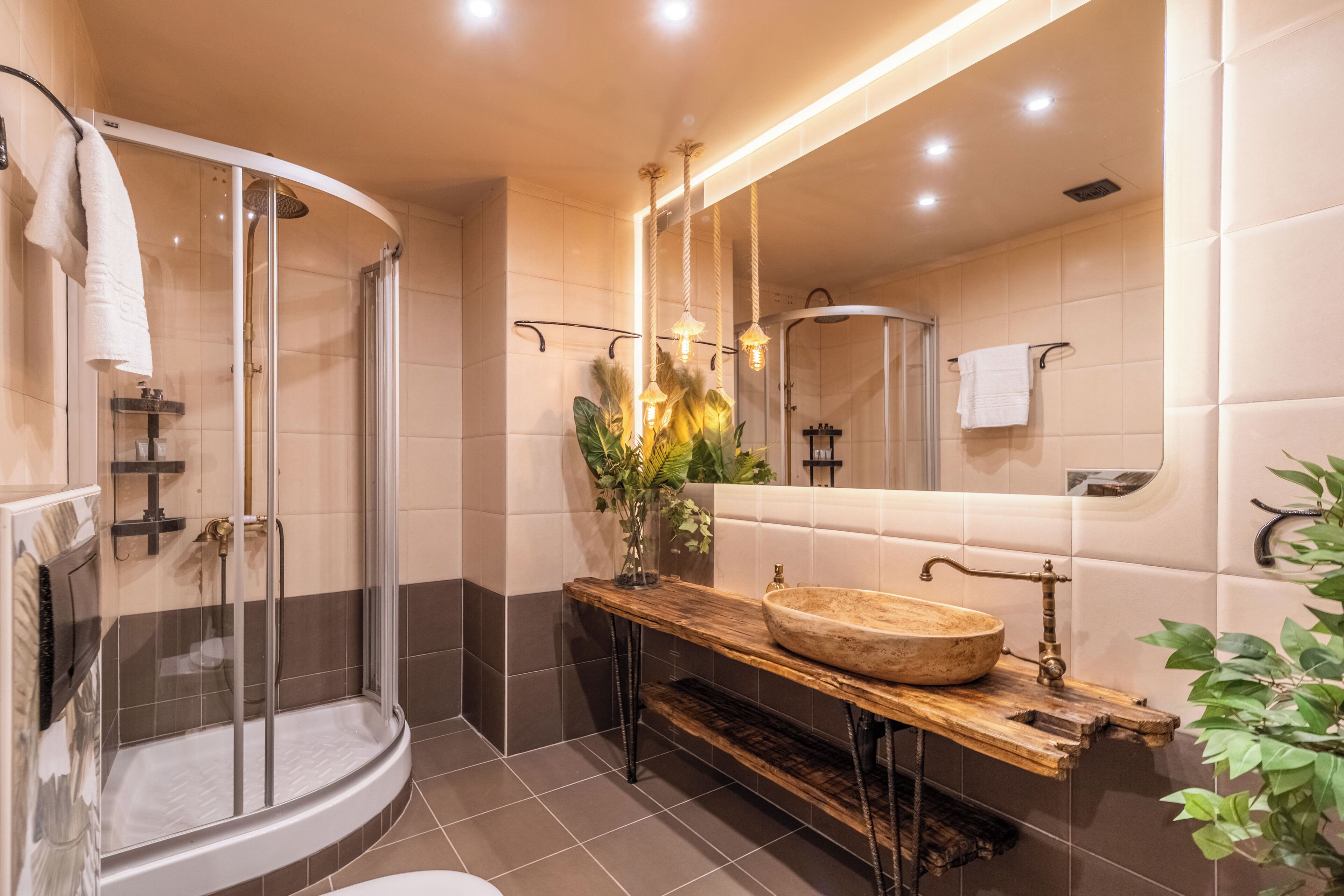 A modern bathroom with a glass-enclosed shower, a wooden vanity with a bowl sink, and a large mirror.