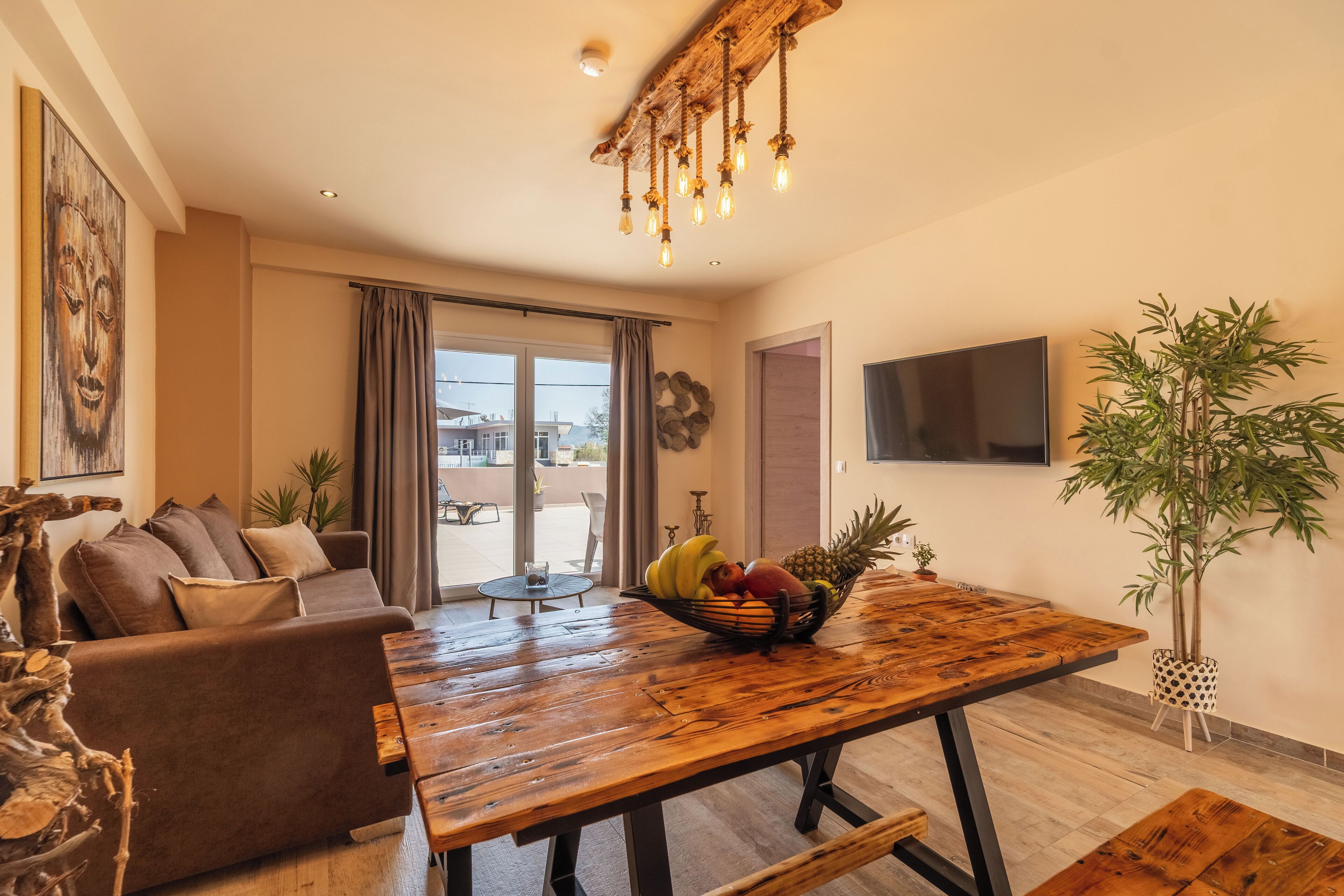 A modern living room with a wooden dining table, a brown sofa, and a large window.