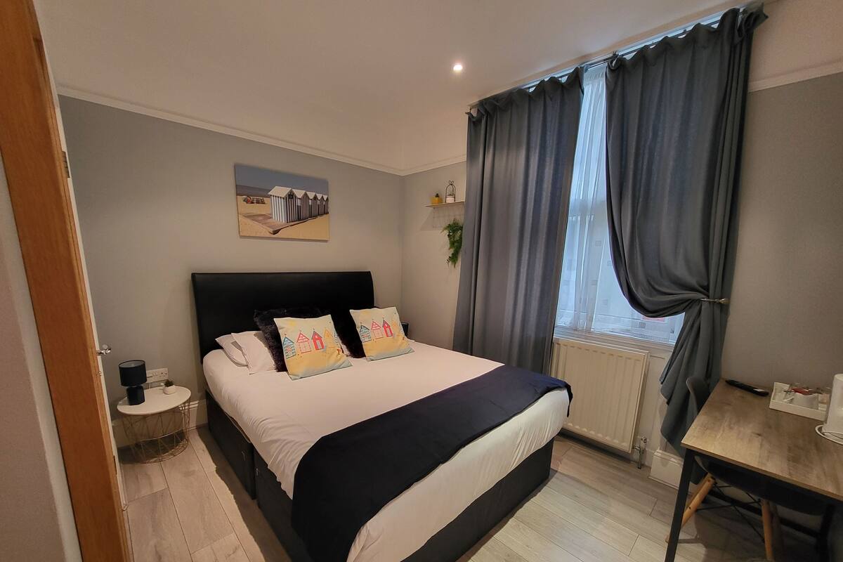A bedroom with a bed, bedside table, and a window with curtains.