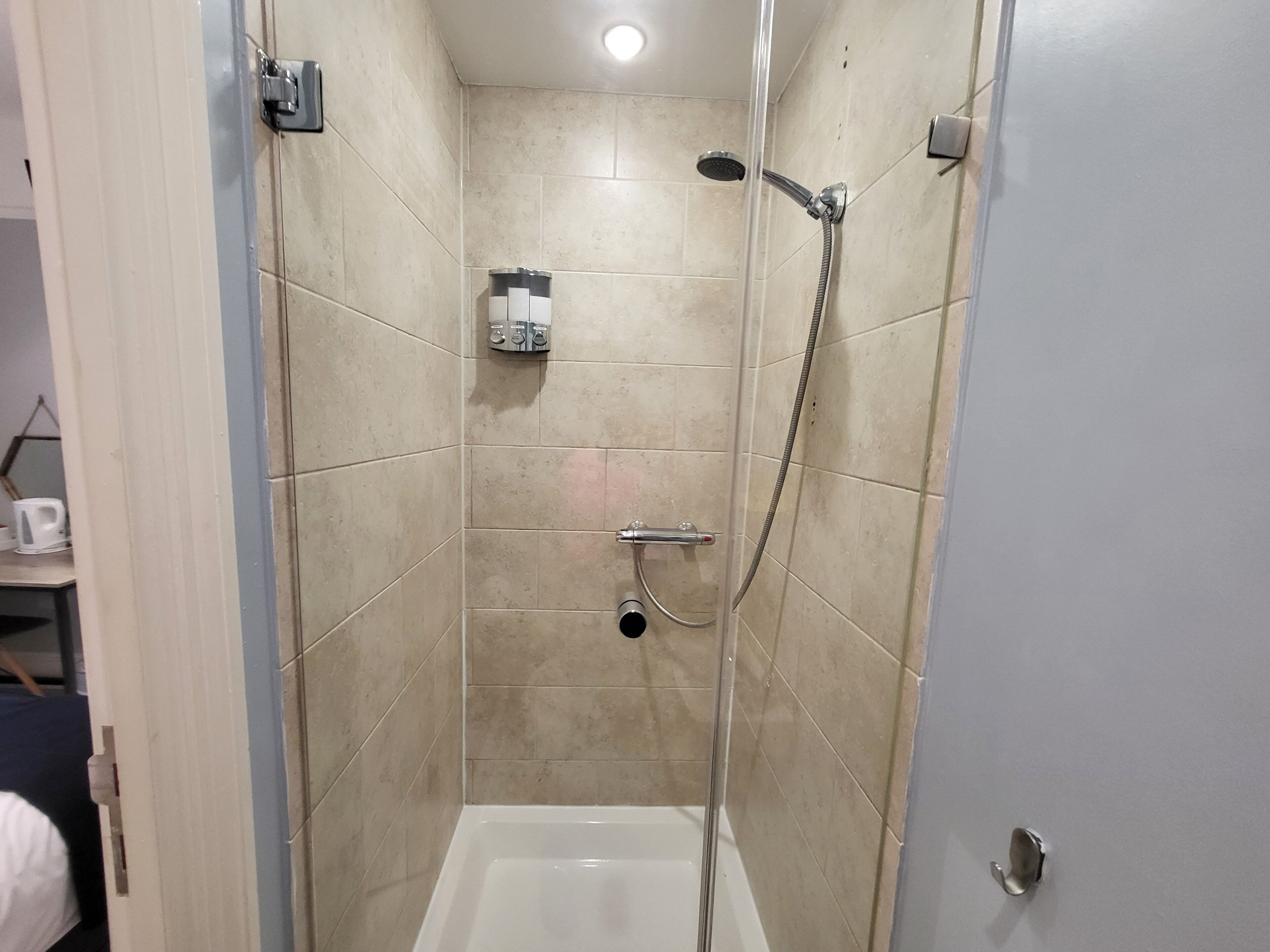 A small, enclosed shower area with a handheld showerhead and a wall-mounted faucet.