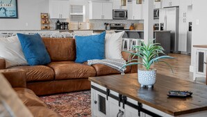 A modern living room with a brown leather sofa, a wooden coffee table, and a potted plant. - Beautiful Lake Views, Indoor and Outdoor Pool, Private Hot Tub, and Game Room! (Branson)