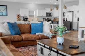 A modern living room with a brown leather sofa, a wooden coffee table, and a potted plant.