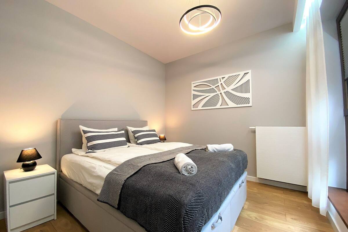 A neatly made bed with a striped pillow, a bedside lamp, and a modern wall art piece.