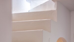 Un interno bianco con una scala che conduce a una porta ad arco.