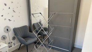 A room with a grey chair, a metal drying rack, and a wardrobe with a grey door.
