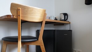 A kitchen with a wooden chair, a black refrigerator, and a shelf with a kettle and cups. - Vogahraun 4 (Myvatn)