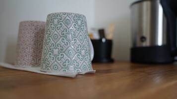Deux tasses à motifs posées sur une surface en bois, avec un appareil en acier inoxydable en arrière-plan.