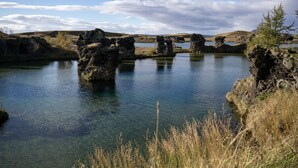 A natural landscape with clear water, rocky formations, and sparse vegetation.
