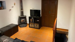 Een woonkamer met een open haard, een televisie en een houten deur.