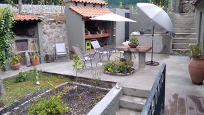 Een terras met een tafel en stoelen, omringd door potplanten en een kleine tuin.