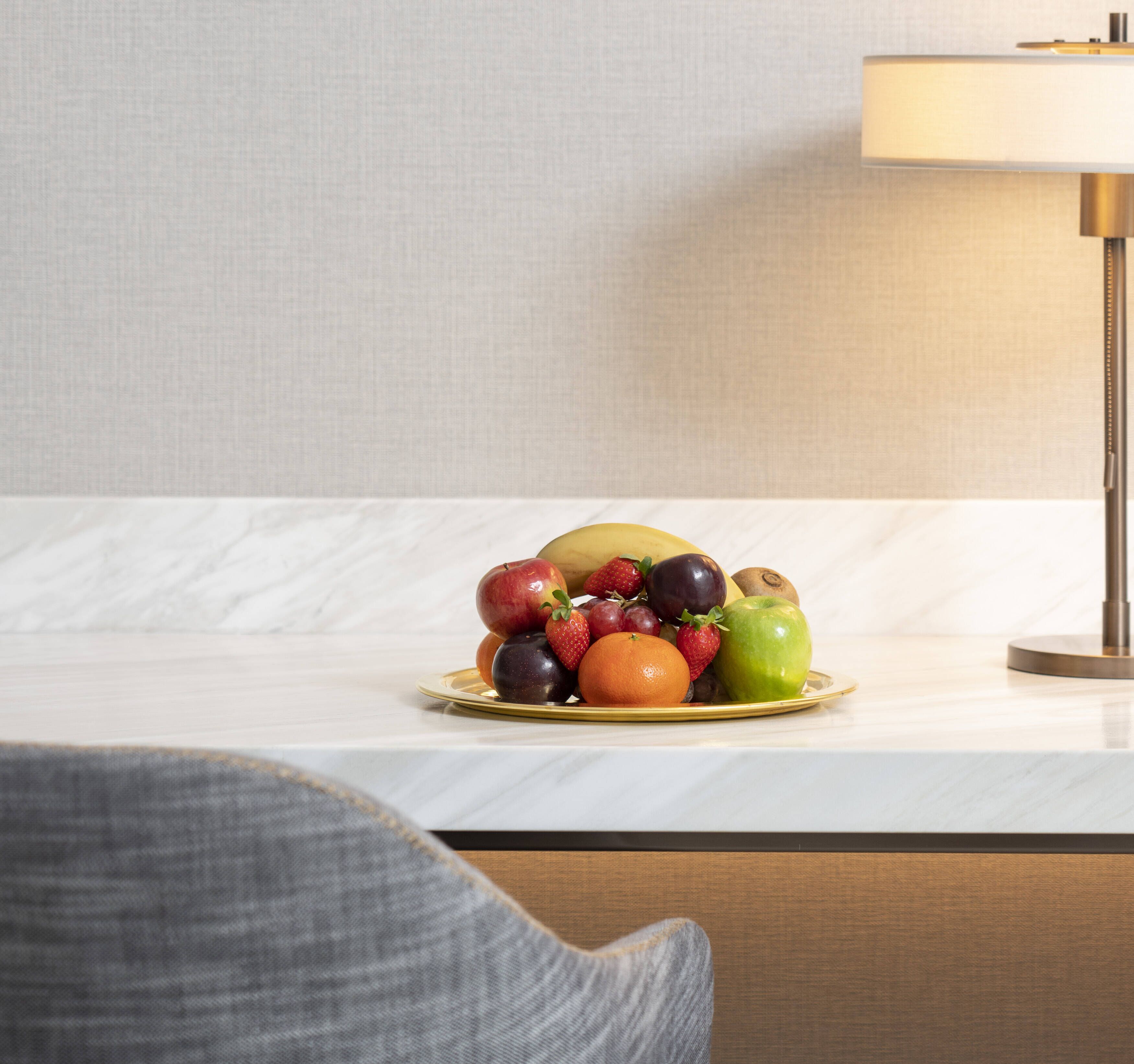 A fruit platter on a table with a lamp in the background.