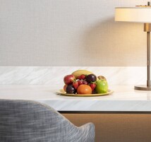 Eine Obstplatte auf einem Tisch, im Hintergrund steht eine Lampe.