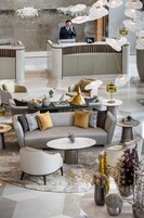 A modern lobby with a reception desk, seating area, and decorative vases.