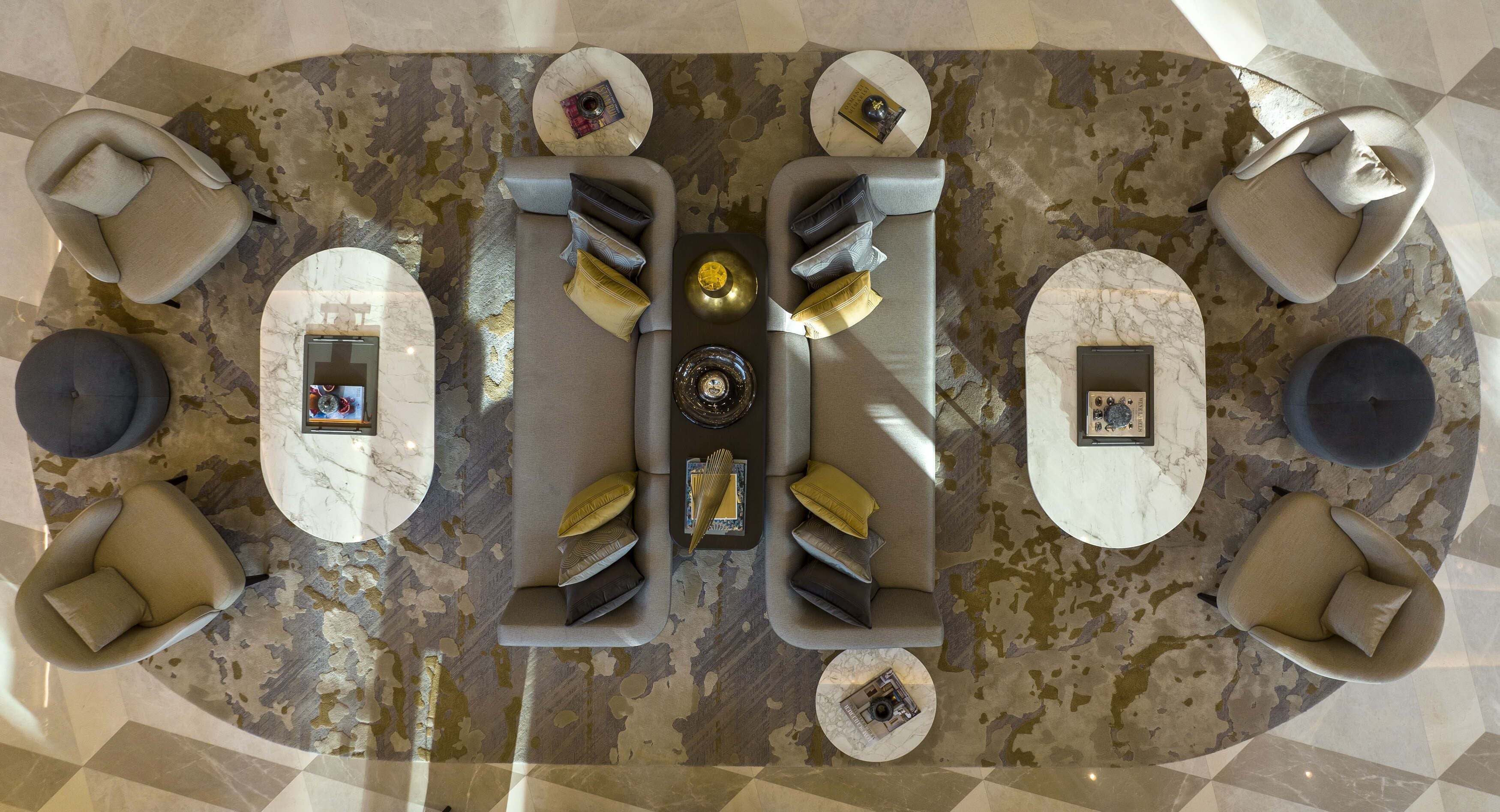 A modern lounge area with a central sofa, four armchairs, and a coffee table, all arranged on a patterned floor.