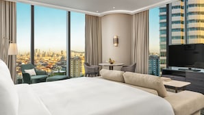 A hotel room with a large bed, a TV, a small table with a bowl of fruit, and a view of the cityscape. - Address Istanbul (Istanbul)