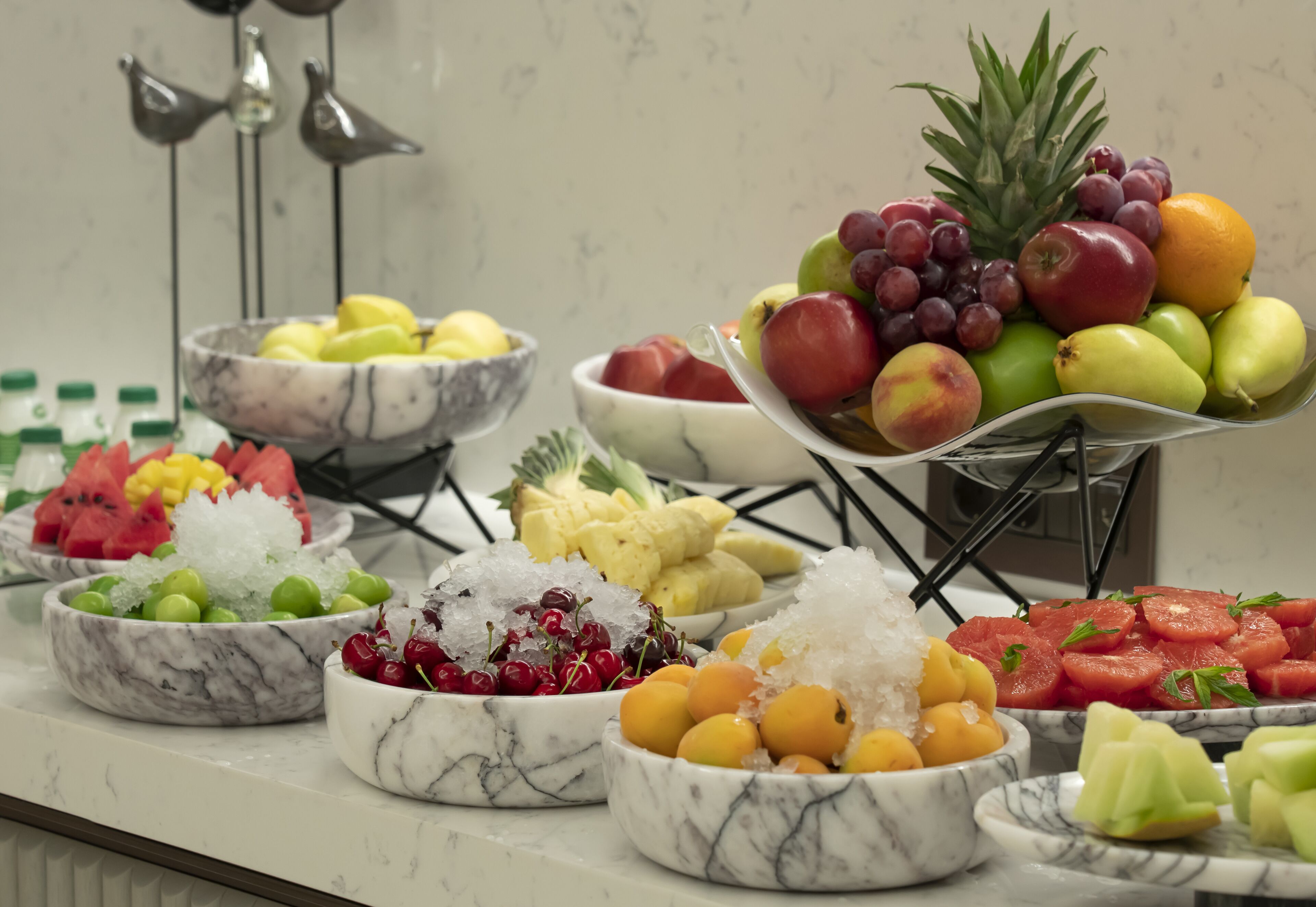 A buffet with various fruits and vegetables arranged on a marble countertop.
