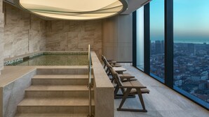 A modern indoor pool area with a view of a cityscape through large windows. - Address Istanbul (Istanbul)