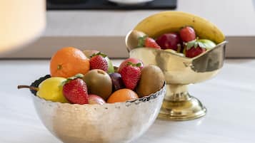 Dos tazones metálicos repletos de frutas sobre una mesa.
