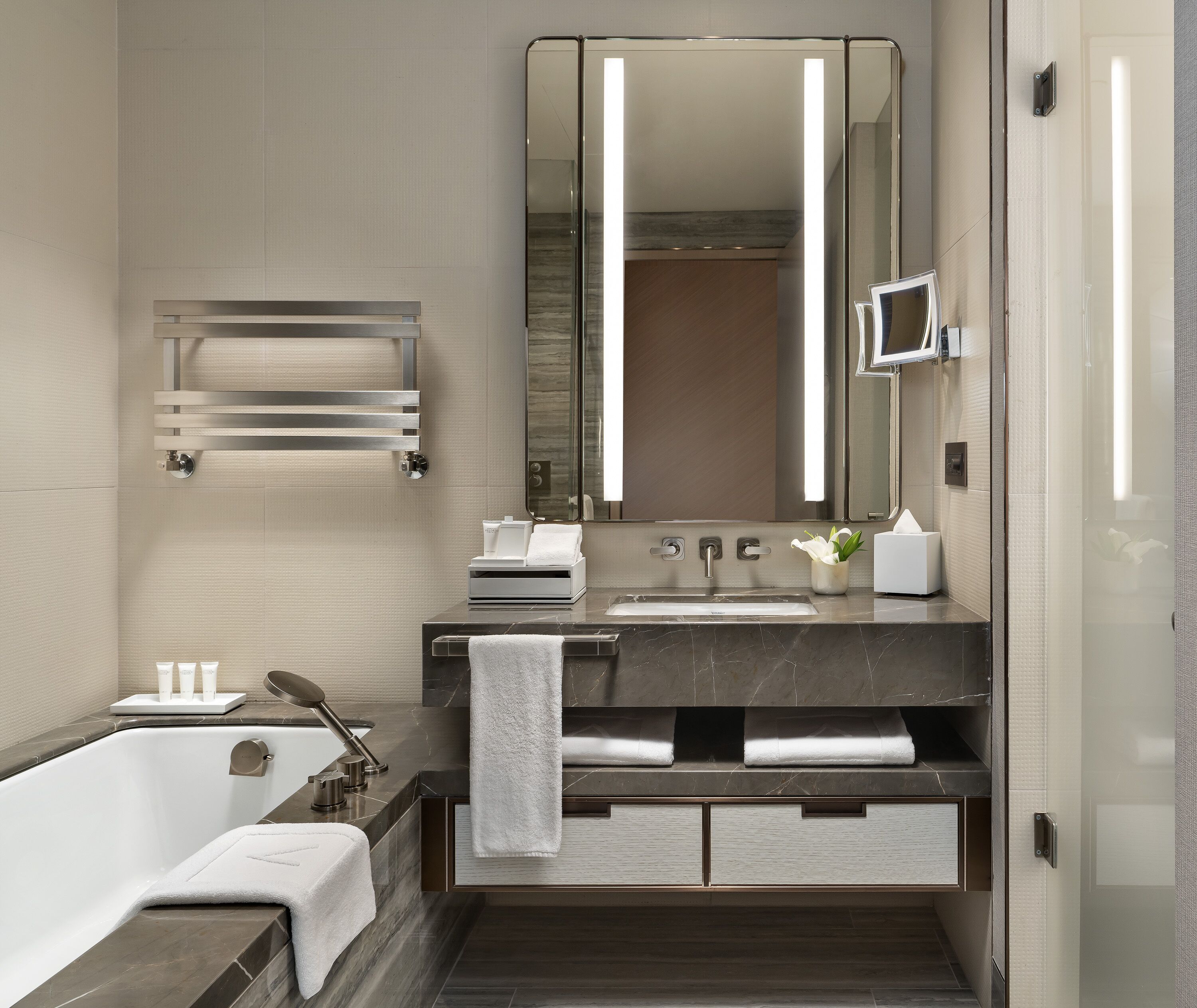 Un baño moderno con bañera, tocador con espejo y un perchero para toallas.