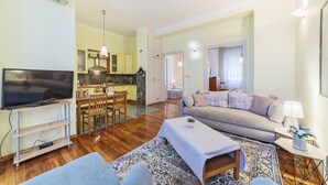 A living room with a flat-screen TV, a sofa, a coffee table, and a dining area with a table and chairs. - Awesome Apartment in Pula With Wifi and 2 Bedrooms (Pula)