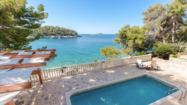 A stone deck with a swimming pool, wooden pergola, and a view of the sea. - Awesome Home in Prizba With Wifi and 3 Bedrooms (Blato)