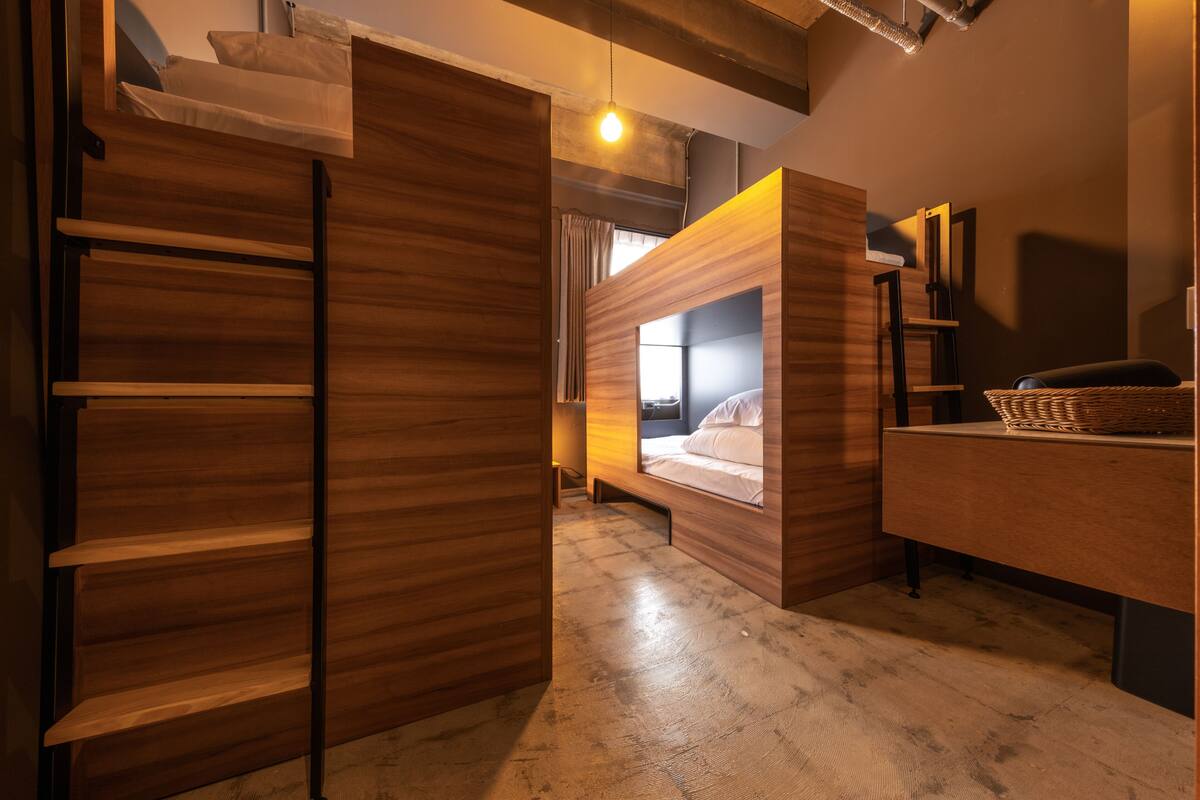 Una habitación moderna con literas, un armario de madera y un escritorio con una cesta.