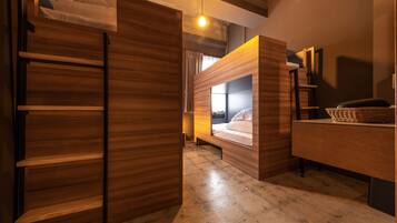 A modern room with a bunk bed, wooden wardrobe, and a desk with a basket.