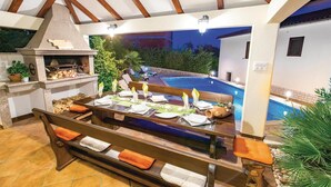 An outdoor dining area with a pool, a barbecue grill, and a view of the pool and trees. - Stunning Home in Rijeka With Wifi and 2 Bedrooms (Rijeka)