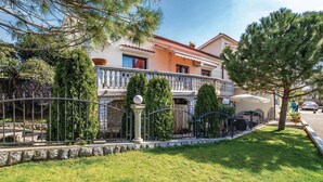 A two-story house with a balcony, a stone wall, and a well-maintained lawn. - Stunning Home in Rijeka With Wifi and 2 Bedrooms (Rijeka)