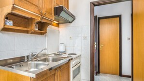 A kitchen with wooden cabinets, a stainless steel sink, a coffee maker, and a white oven. - Awesome Home in Silo With Wifi and 2 Bedrooms (Dobrinj)