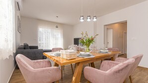 A dining area with a wooden table set for six, surrounded by pink upholstered chairs.