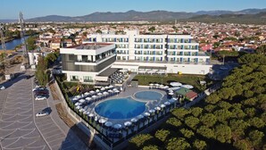 Un hotel con piscina en la azotea, estacionamiento y vistas de la ciudad.