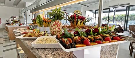 A buffet with various food items and fresh fruits.