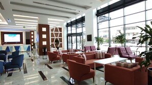 Un moderno vestíbulo de hotel con mostrador de recepción, zona de estar y amplios ventanales.