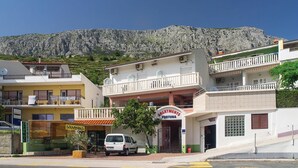 Un edificio con un letrero que dice "APARTMENTS FORTUNA" y una camioneta blanca estacionada adelante.