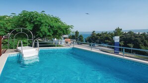 Una piscina con vista al mar, rodeada de árboles y un letrero para los apartamentos hotel Sagitta.