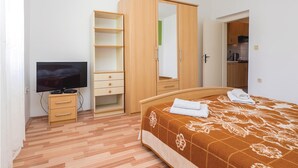Un dormitorio con cama, televisión, armario y una pequeña kitchenette.