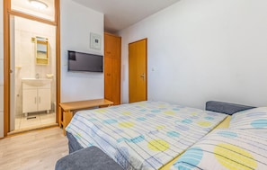 A bedroom with a bed, a TV mounted on the wall, a wooden desk, a mirror, and a bathroom with a sink and toilet. - Stunning Home in Medulin With Wifi and 2 Bedrooms (Medulin)